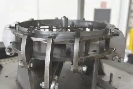 Close-up of a custom machined metal welding fixture used for clamping and positioning circular components during welding or assembly.