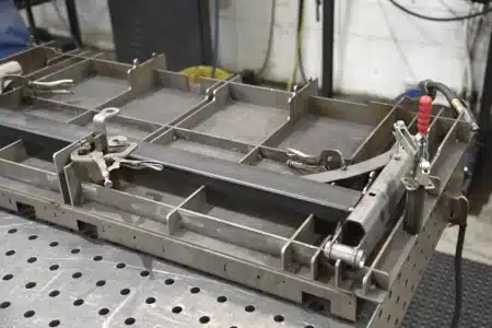 Custom welding fixture setup with clamps and support structures for holding metal tubing during fabrication.