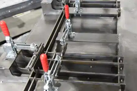 Custom welding fixture equipped with toggle clamps for precise positioning and holding of sheet metal components.