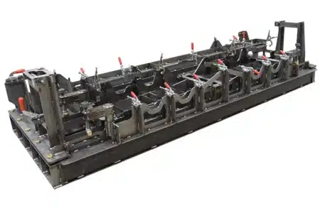 Large-scale custom welding fixture with multiple clamps for precise alignment and secure positioning of complex assemblies.
