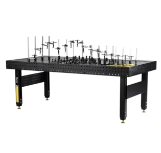 The 48" x 96" x 6" Stationary Nitride Welding Table with 80 Piece Fixturing Kit features a black perforated surface, adjustable clamps and fixtures, and sturdy legs with leveling feet for stability.