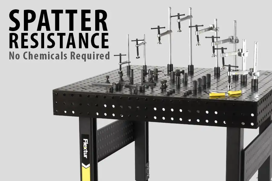 A black metal workbench with clamps and fixtures on top. Large text reads “SPATTER RESISTANCE,” with “No Chemicals Required” beneath—an ideal choice as EPA bans methylene chloride. The bench features “Flextur” branding on the leg.